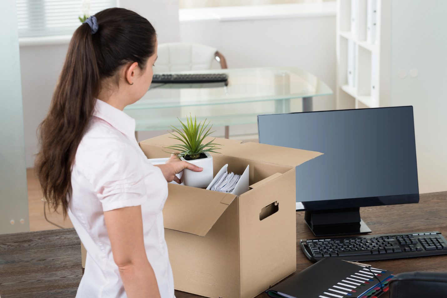 Employee packing office equipment and documents into a box during a business move