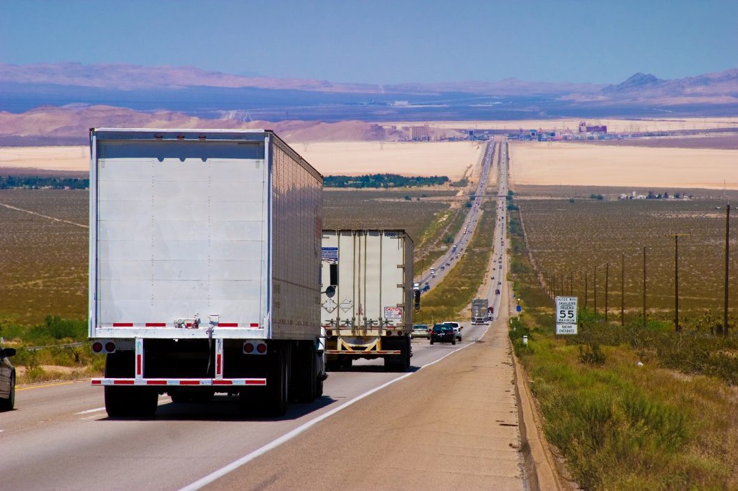 Moving trucks travelling on a long highway during a long-distance move.