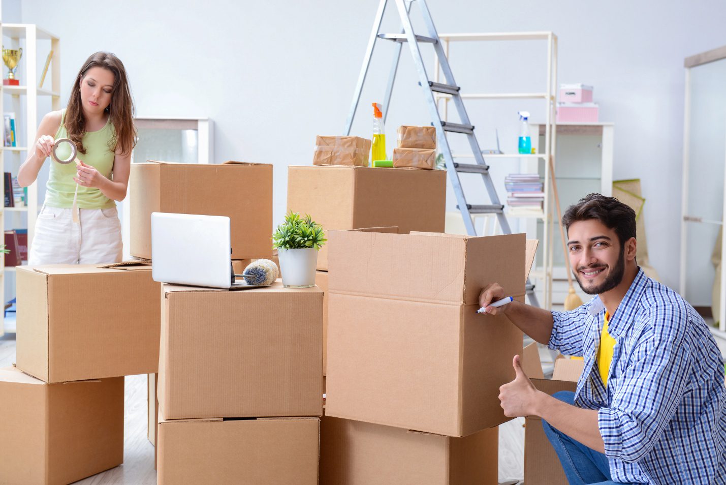 Couple packing moving boxes and household essentials for a move