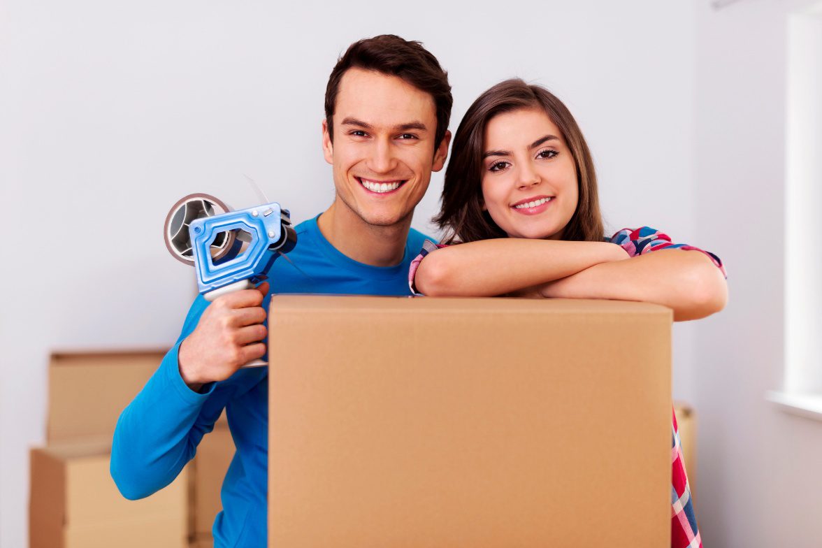 Couple packing for a move with cardboard boxes and packing tape.