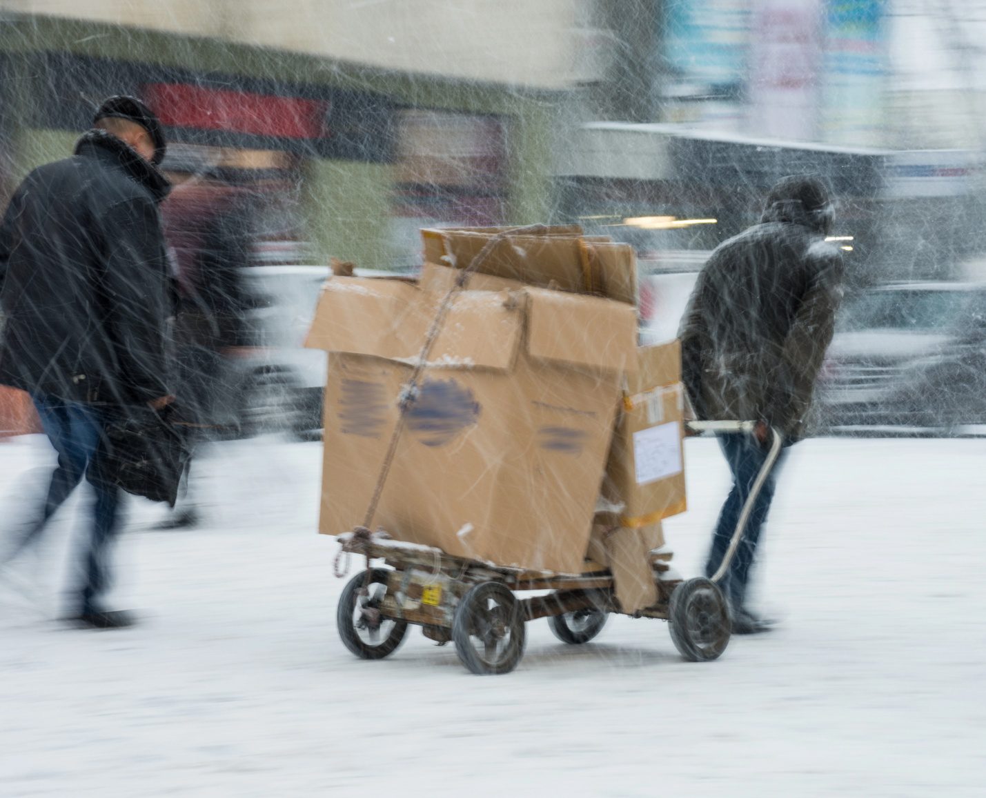 Movers transporting boxes through heavy snow during a winter move